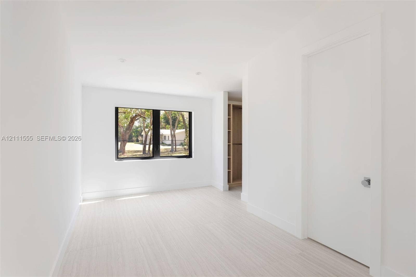 8800 SW 118th Street, Miami, Miami, FL 33176 Bright room featuring light wood-finish flooring, a black-framed window, recessed lighting, and built-in closet shelving