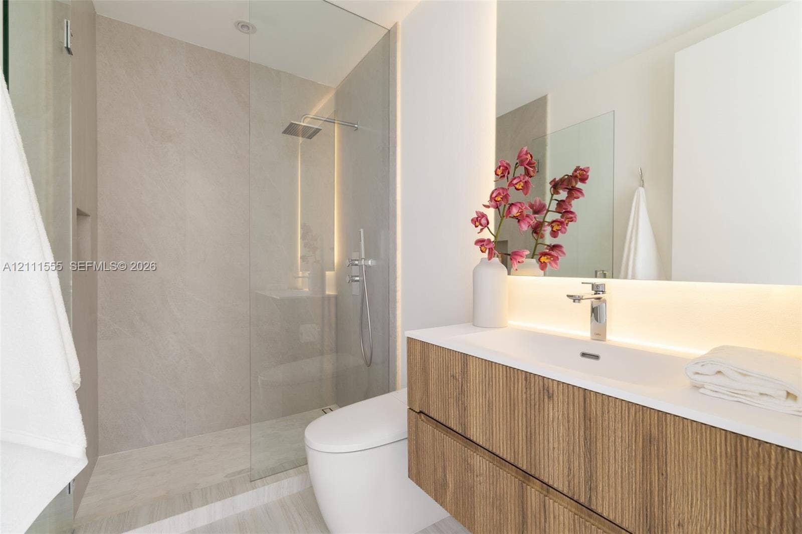 8800 SW 118th Street, Miami, Miami, FL 33176 Floating wood-finish vanity with an integrated sink, walk-in glass-enclosed shower featuring large-format tile surround, rain-style showerhead, and integrated backlighting