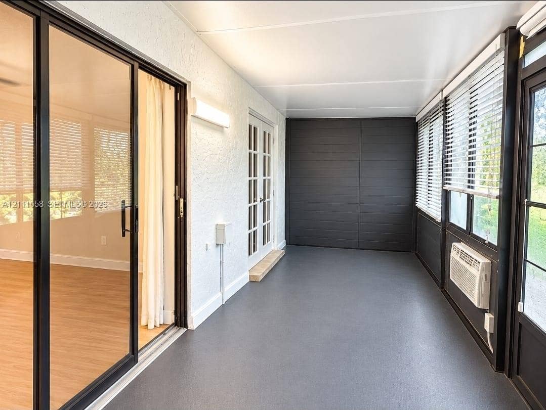 3652 NW 83rd Lane, #3652, Sunrise, Sunrise, FL 33351 Enclosed porch featuring charcoal-toned flooring, expansive glass sliding doors, dual-pane windows with integrated blinds, French entry doors, and a wall-mounted climate control unit