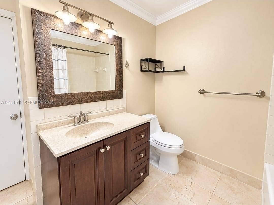 3652 NW 83rd Lane, #3652, Sunrise, Sunrise, FL 33351 Dark wood-finish vanity with a stone-composite countertop, integrated sink, three-light fixture, framed wall mirror, and neutral tile flooring