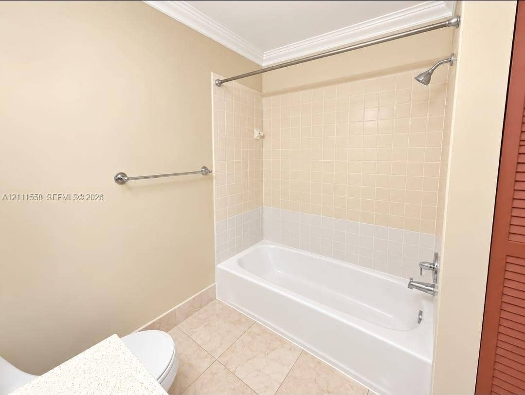 3652 NW 83rd Lane, #3652, Sunrise, Sunrise, FL 33351 Bathroom featuring a porcelain tub with tile surround, stainless steel shower fixtures, neutral tile flooring, and a stone-surface vanity