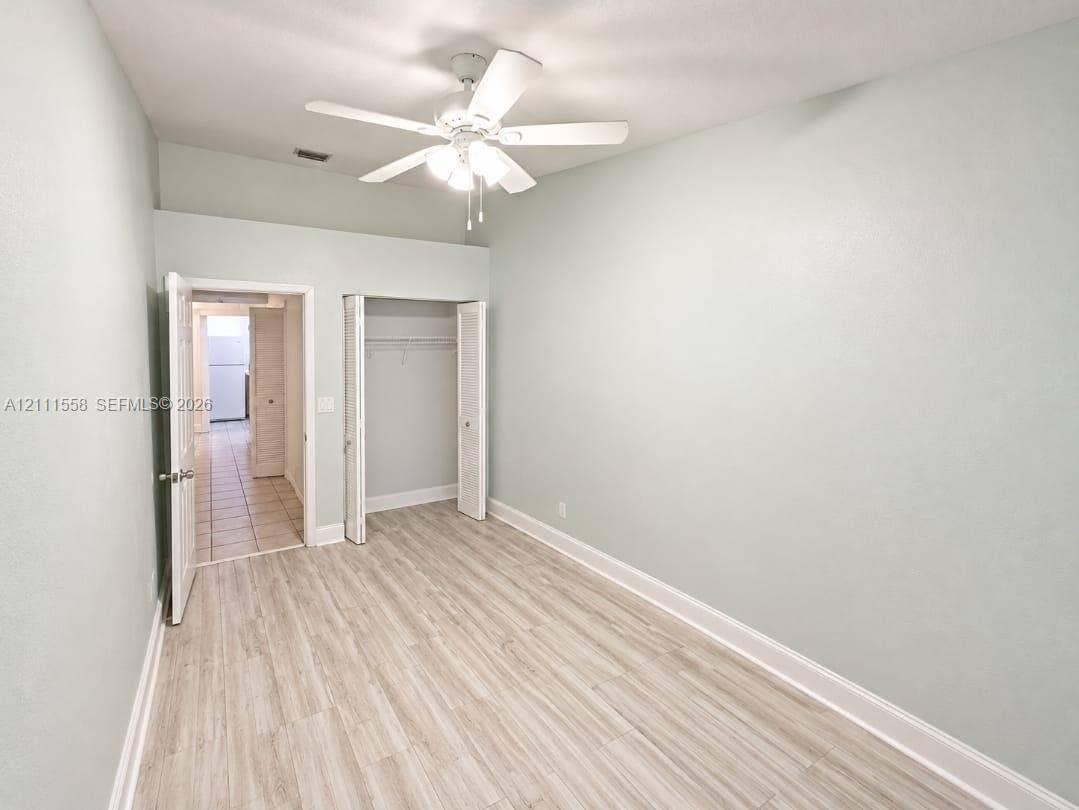 3652 NW 83rd Lane, #3652, Sunrise, Sunrise, FL 33351 Room featuring wood-finish flooring, a ceiling fan with integrated lighting, and a reach-in closet with double-hinged doors