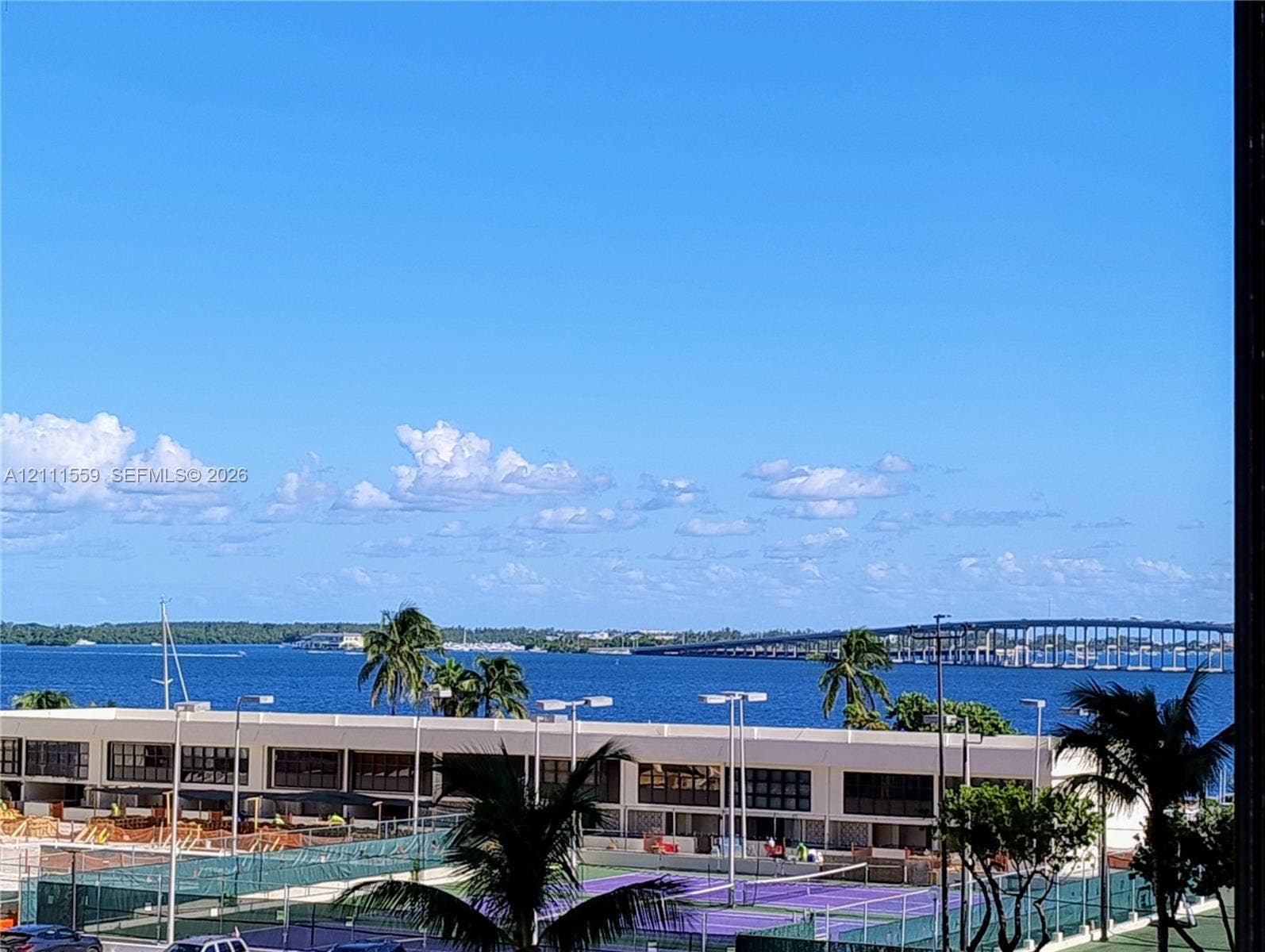 1915 Brickell Avenue, #C501, Miami, FL 33129 Open water backdrop featuring a bridge, palm trees, and outdoor tennis courts