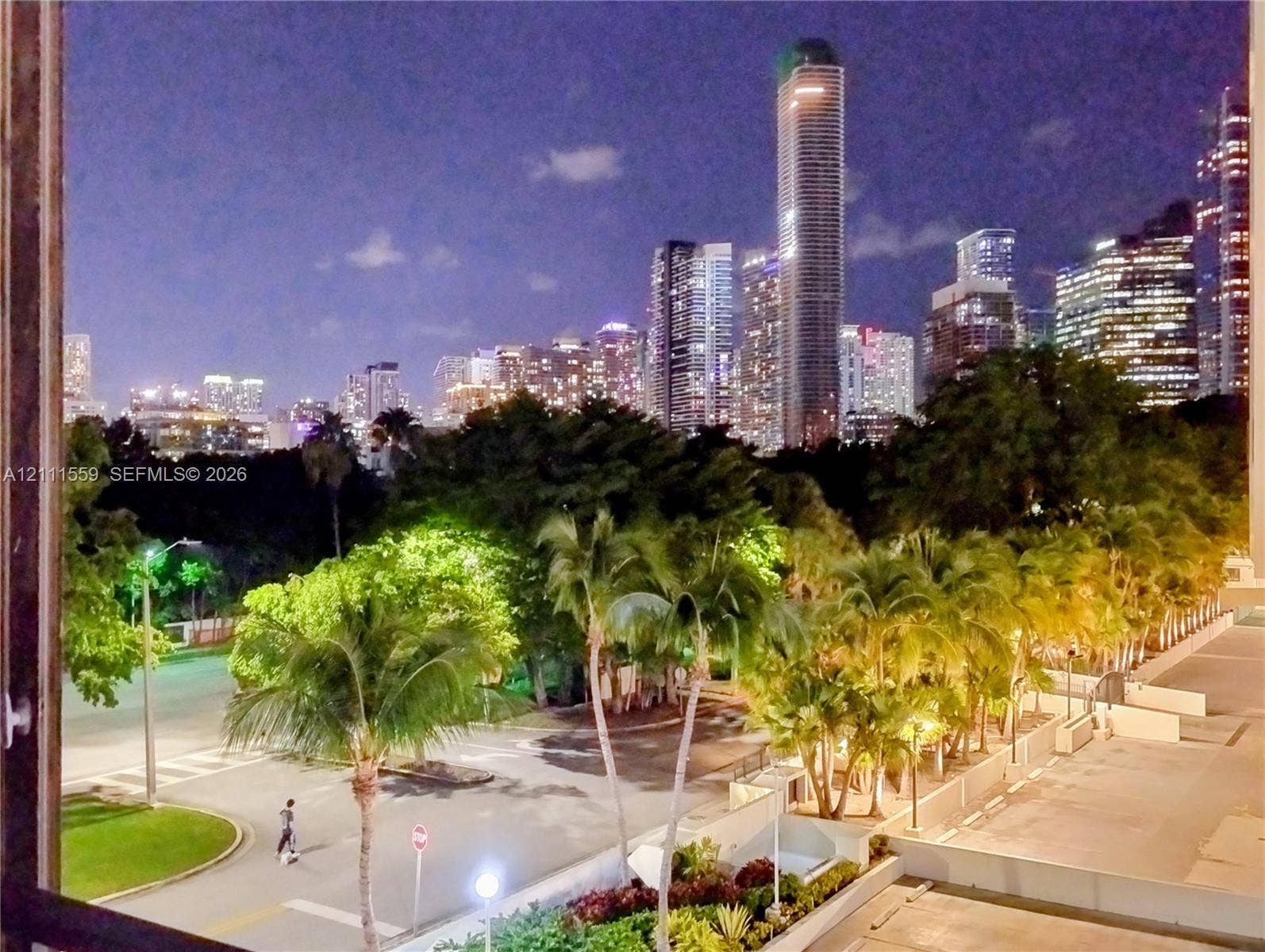 1915 Brickell Avenue, #C501, Miami, FL 33129 Panoramic cityscape featuring illuminated high-rise towers, mature palm trees, and landscaped grounds