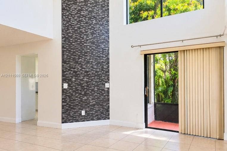 3539 W Inverrary Boulevard W, #1, Lauderhill, Lauderhill, FL 33319 Double-height ceilings, floor-to-ceiling dark stone-tile accent wall, neutral ceramic tile flooring, and sliding glass door with external patio access