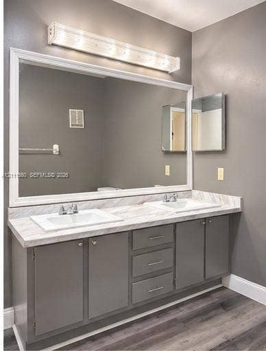 3539 W Inverrary Boulevard W, #1, Lauderhill, Lauderhill, FL 33319 Dual-sink vanity featuring a light-toned stone-patterned countertop, charcoal-toned cabinetry with integrated storage drawers, a large framed wall mirror, and a linear overhead light fixture
