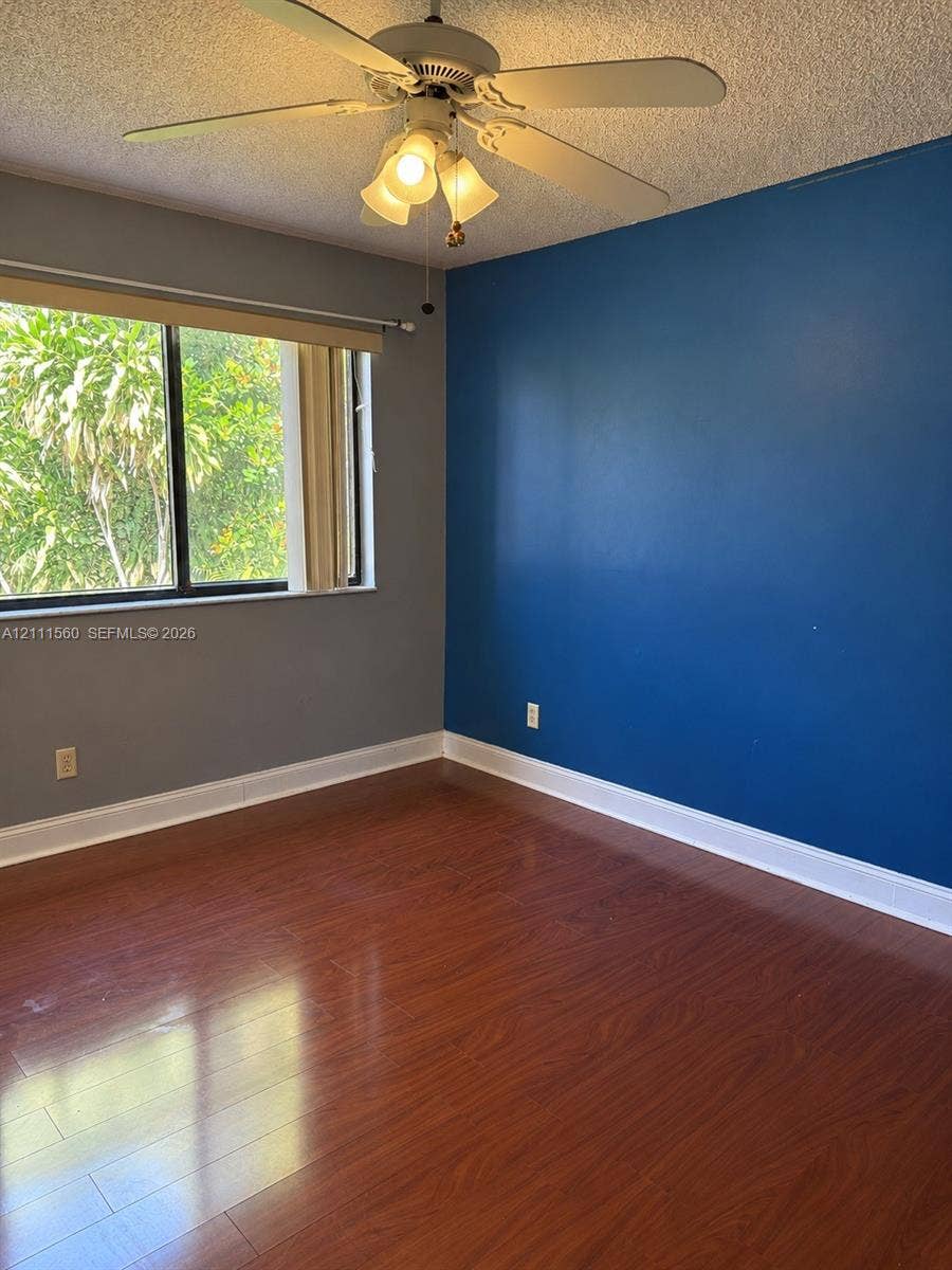 3539 W Inverrary Boulevard W, #1, Lauderhill, Lauderhill, FL 33319 Wood-finish flooring, accent wall, ceiling fan with light fixture, and horizontal window