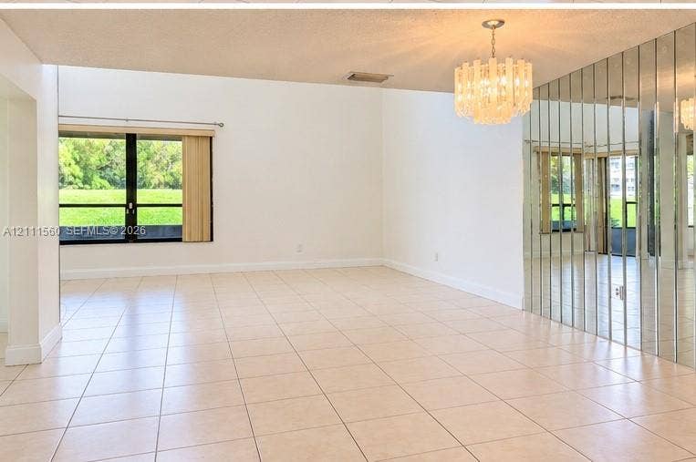 3539 W Inverrary Boulevard W, #1, Lauderhill, Lauderhill, FL 33319 Spacious living area featuring large-format tile flooring, a floor-to-ceiling mirrored wall, a multi-tiered crystal chandelier, and oversized windows