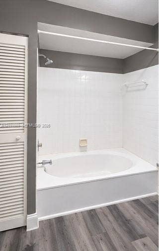 3539 W Inverrary Boulevard W, #1, Lauderhill, Lauderhill, FL 33319 Oval soaking tub with a white tile surround, brushed metal fixtures, integrated soap dish, and wood-finish flooring