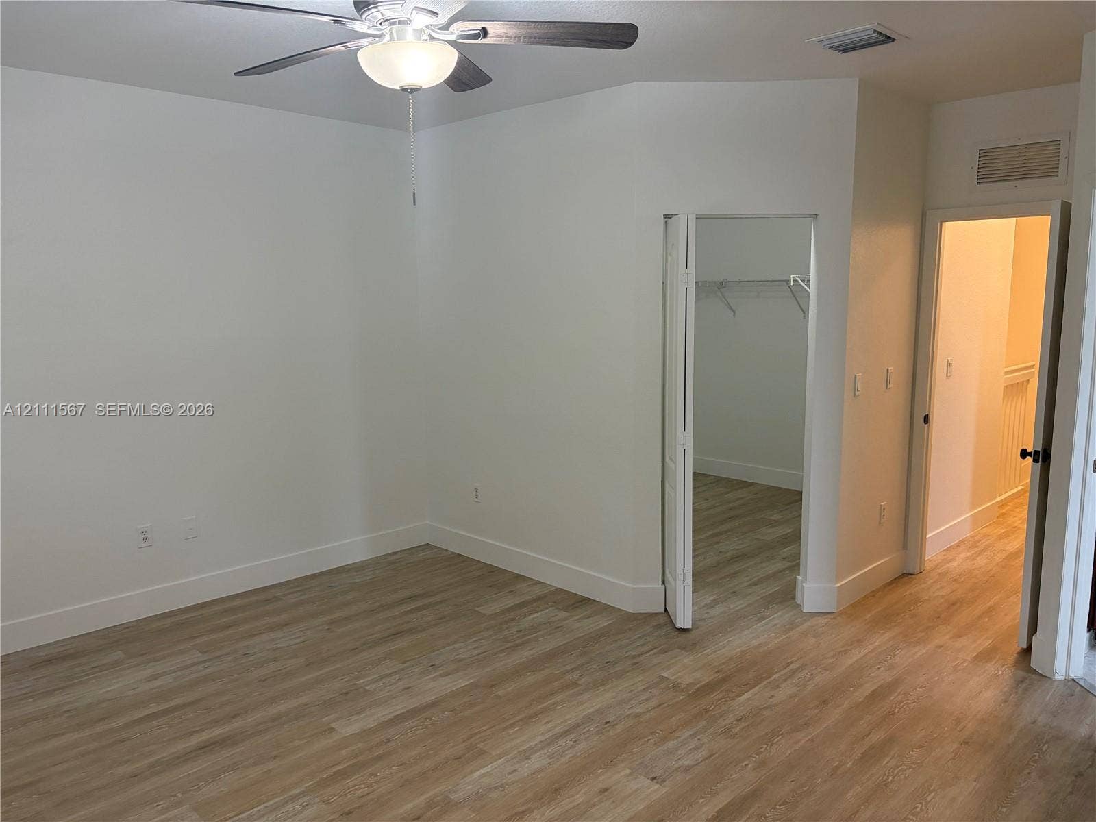 21514 SW 90th Avenue, Cutler Bay, FL 33189 Wood-finish flooring, vaulted ceiling, and ceiling fan with integrated lighting, featuring a walk-in closet with wire shelving