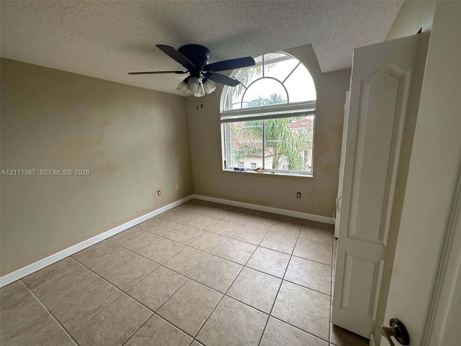 21514 SW 90th Avenue, Cutler Bay, FL 33189 Arched window with decorative muntins, ceramic tile flooring, and integrated ceiling fan with multi-light fixture
