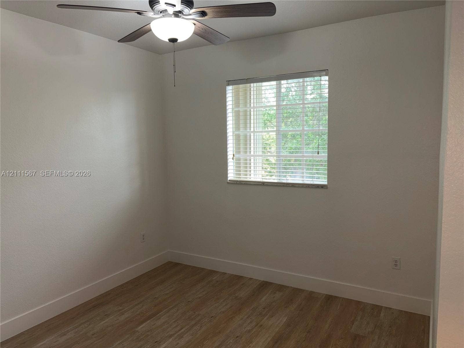 21514 SW 90th Avenue, Cutler Bay, FL 33189 Interior room featuring wood-finish flooring, a multi-blade ceiling fan with integrated light fixture, and a single-pane window with horizontal blinds