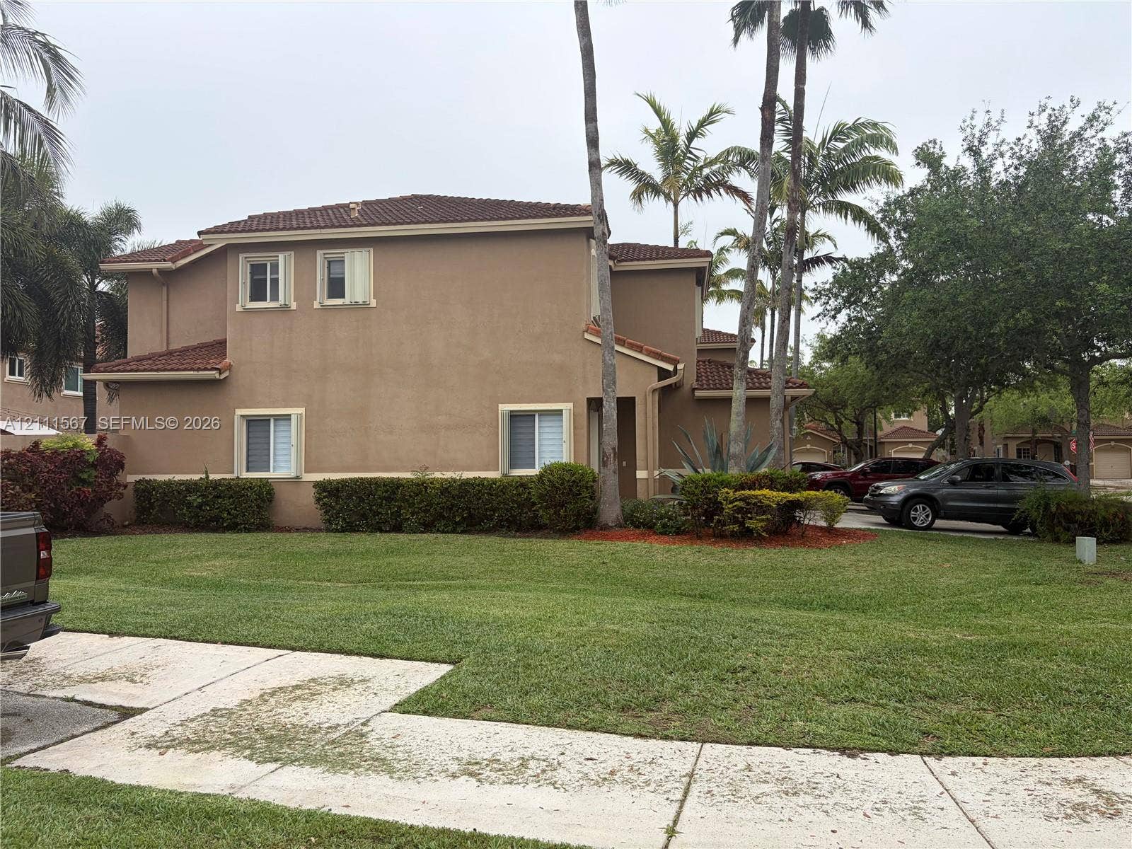 21514 SW 90th Avenue, Cutler Bay, FL 33189 Two-story exterior featuring a stucco facade, clay tile roof, and mature palm trees with manicured landscaping