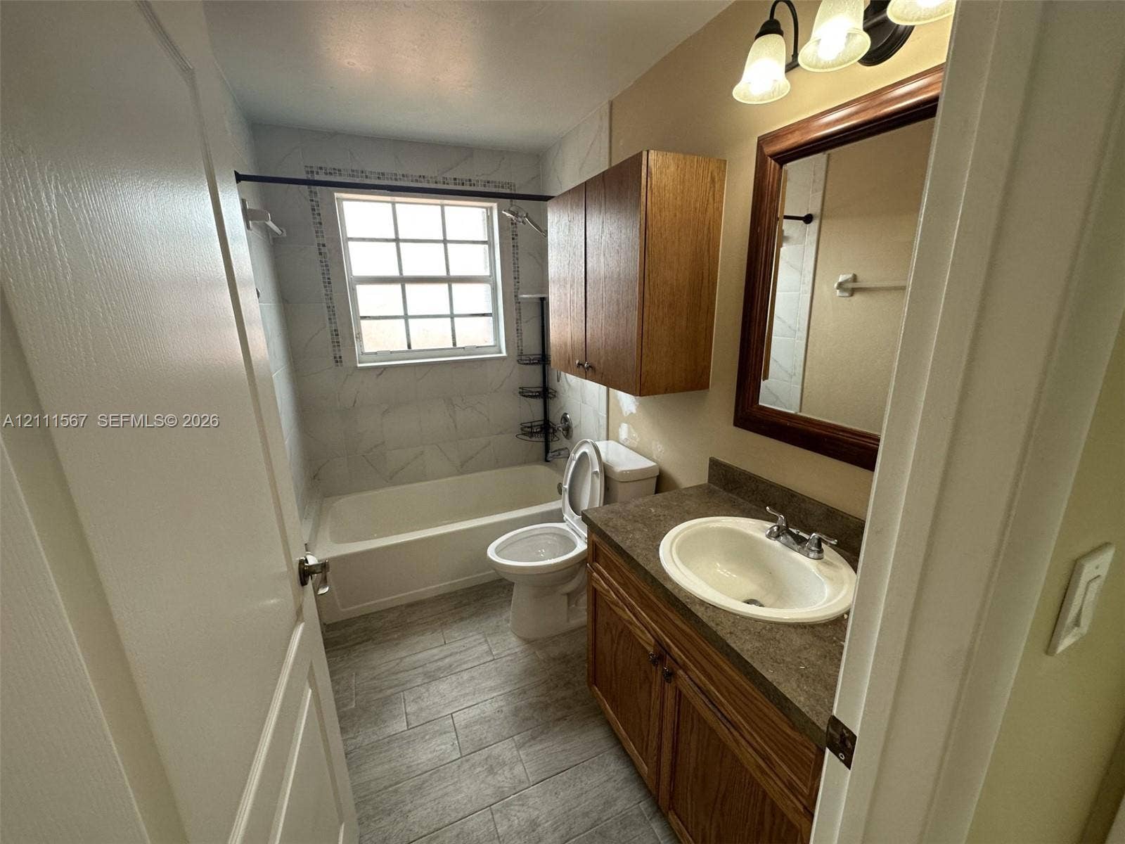 21514 SW 90th Avenue, Cutler Bay, FL 33189 Bathroom featuring a vanity with dark-tone countertop, wood-finish cabinetry, tile-surround tub, and tile flooring