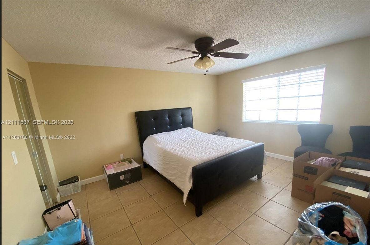21514 SW 90th Avenue, Cutler Bay, FL 33189 Neutral-toned interior featuring ceramic tile flooring, a central ceiling fan with integrated lighting, and horizontal window blinds