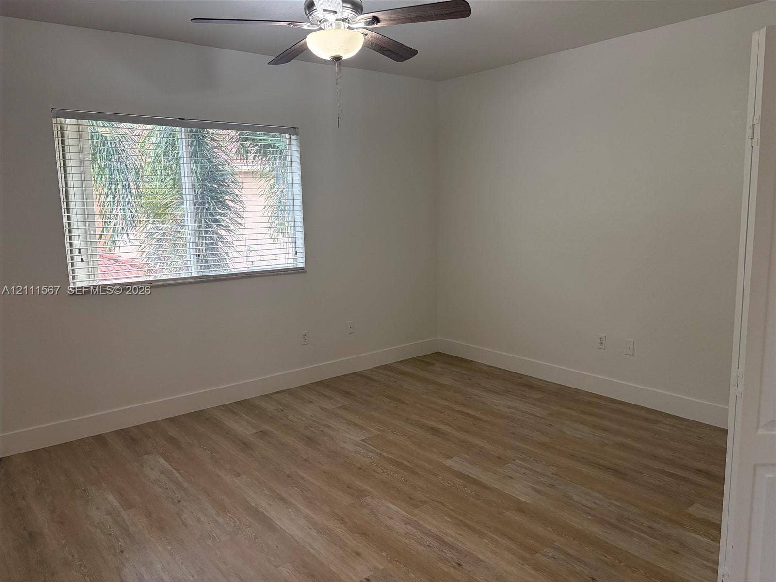 21514 SW 90th Avenue, Cutler Bay, FL 33189 Wood-finish flooring, neutral wall tones, multi-pane window with horizontal blinds, and a ceiling-mounted light fixture with fan