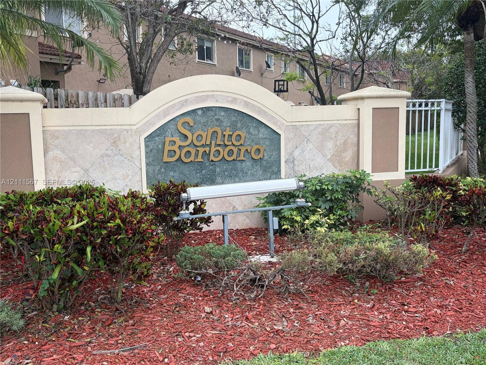 21514 SW 90th Avenue, Cutler Bay, FL 33189 Stucco monument signage featuring stone-tile accents, metal lettering, and integrated landscape lighting, set within a manicured garden bed