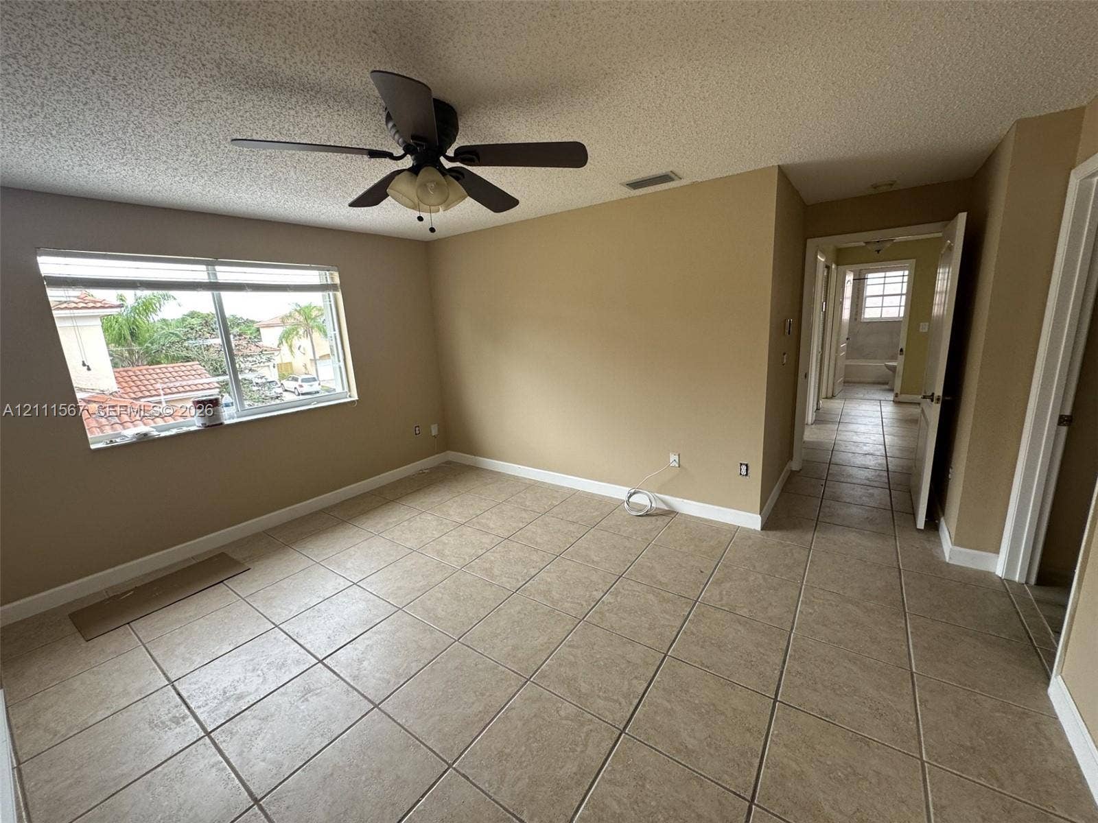 21514 SW 90th Avenue, Cutler Bay, FL 33189 Interior space featuring large-format neutral floor tile, a ceiling fan with integrated lighting, and a window with exterior residential scenery