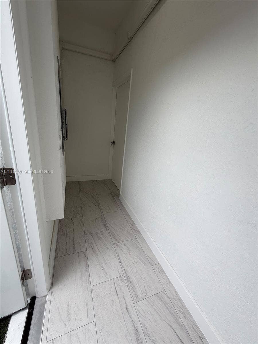 Neutral-toned ceramic tile flooring with a linear pattern, painted walls, and a solid-core swing door
