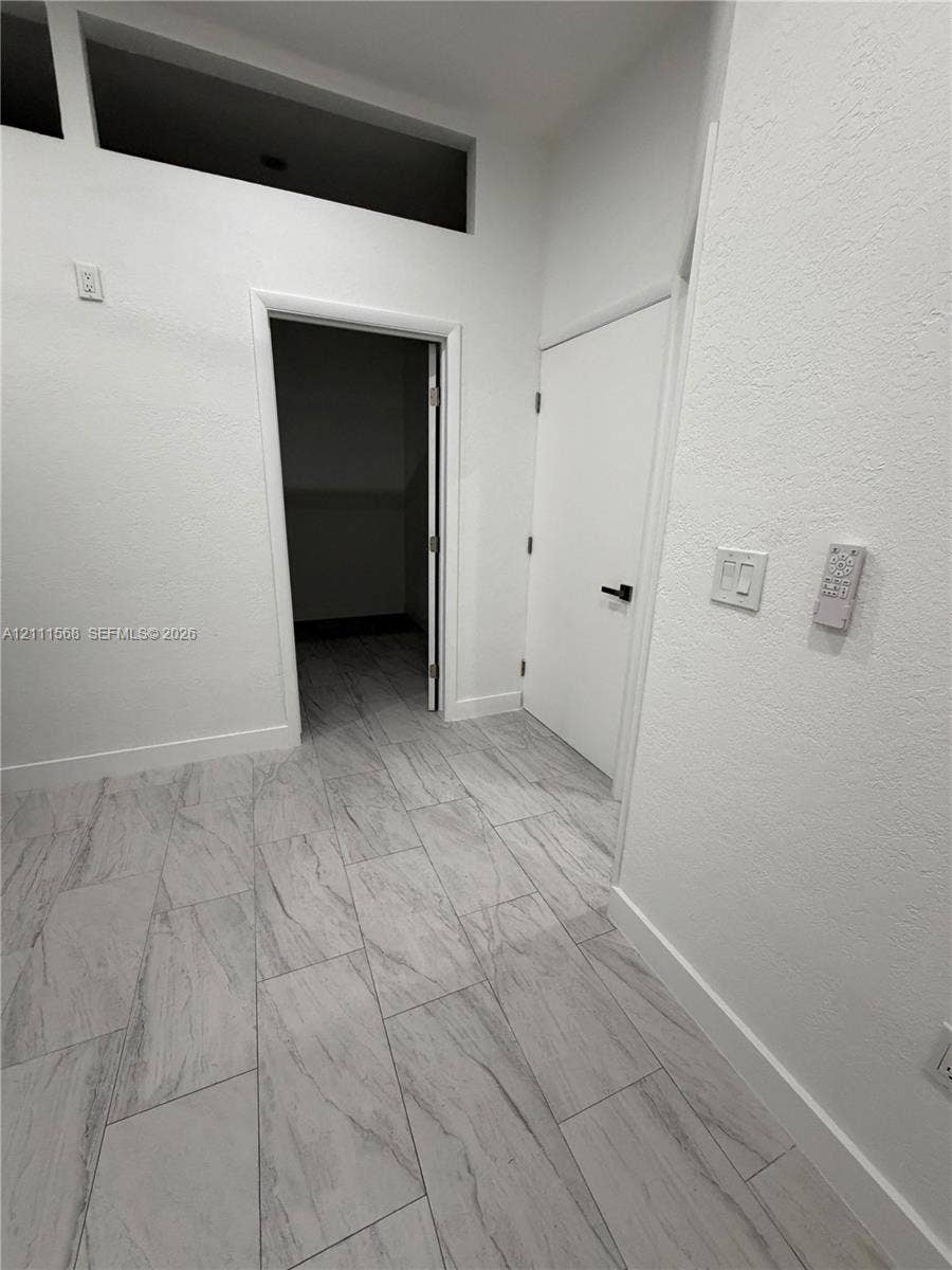 Neutral color palette featuring high-contrast tile flooring, soaring ceilings with rectangular transom windows, and crisp white wall finishes