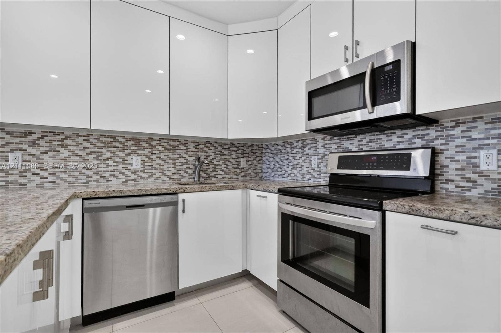 12800 NE 11th Avenue, #4, North Miami, North Miami, FL 33161 Kitchen featuring high-gloss white cabinetry, stone-finish countertops, stainless steel appliances, and a glass-tile mosaic backsplash