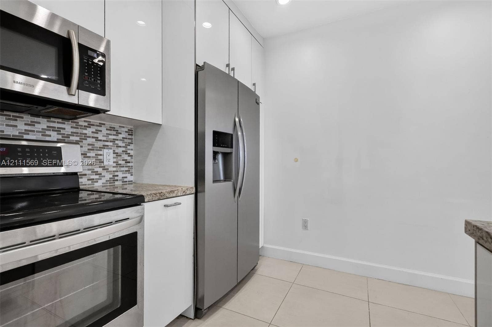 12800 NE 11th Avenue, #4, North Miami, North Miami, FL 33161 Kitchen featuring white gloss cabinetry, stone-finish countertops, stainless steel appliances, and a glass-tile backsplash