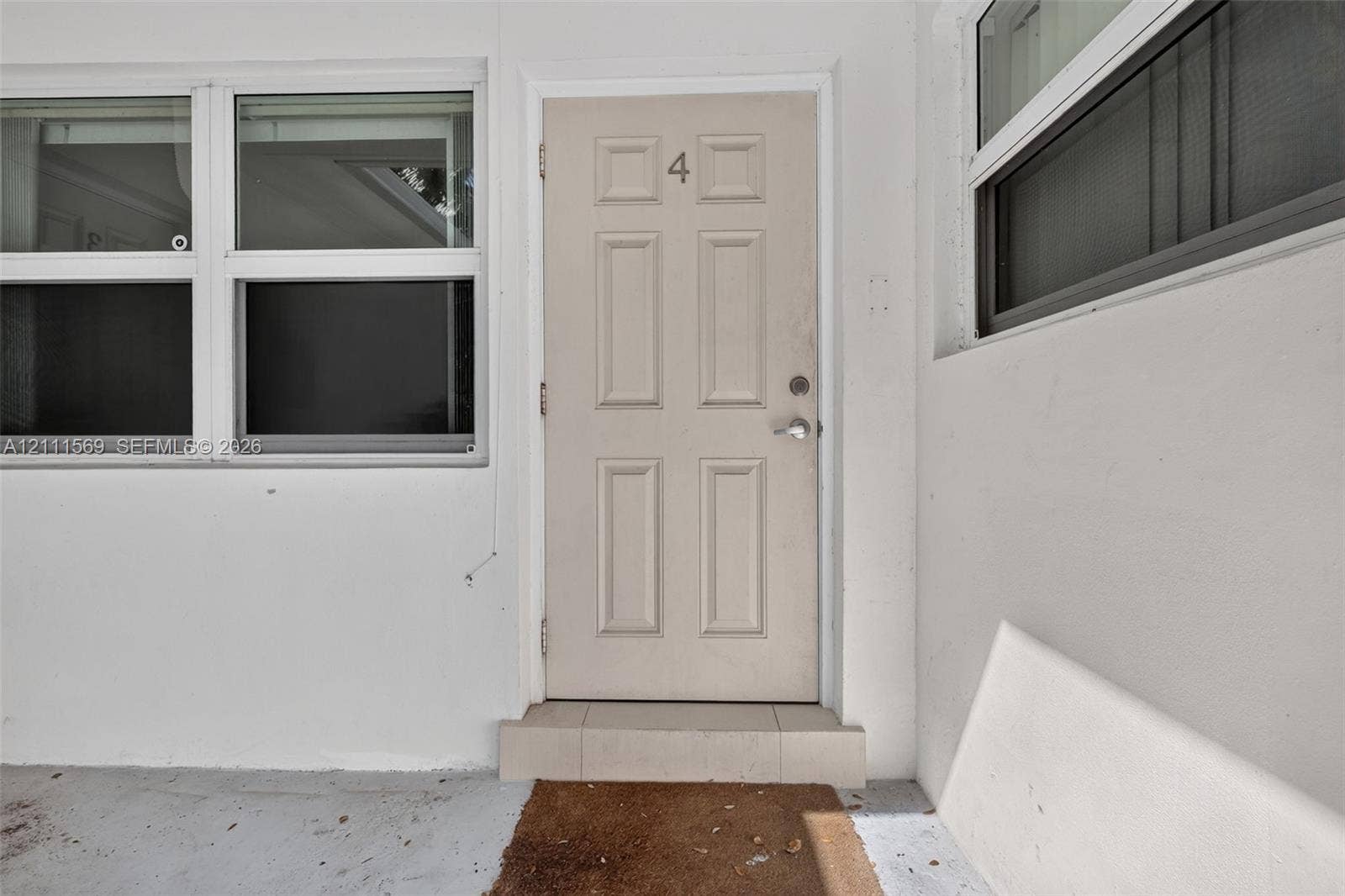 12800 NE 11th Avenue, #4, North Miami, North Miami, FL 33161 Entry featuring a neutral-toned, six-panel door with metallic hardware, accented by large multi-pane windows and a tiered exterior threshold