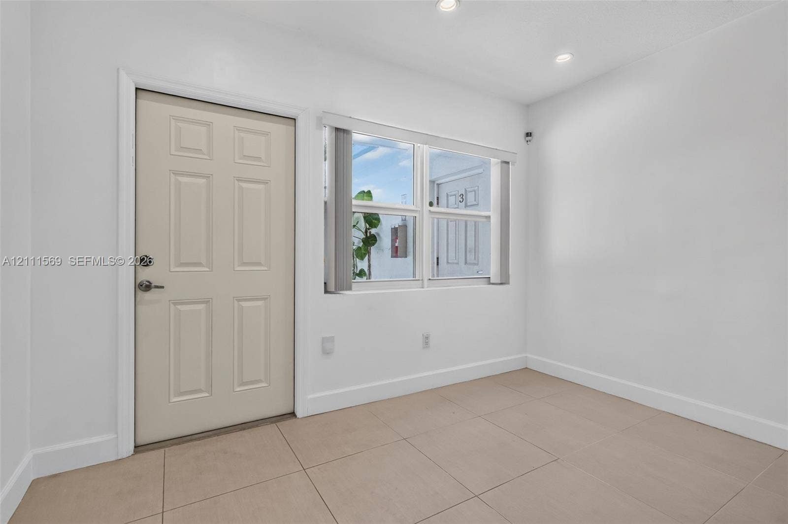 12800 NE 11th Avenue, #4, North Miami, North Miami, FL 33161 Neutral-toned tile flooring, recessed ceiling lighting, and a multi-panel entry door featuring a brushed metal deadbolt and lever handle
