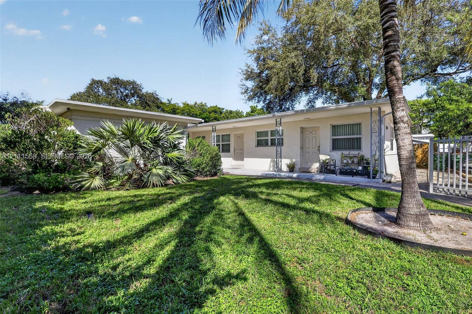 12800 NE 11th Avenue, #4, North Miami, North Miami, FL 33161 Single-story stucco exterior featuring horizontal sliding windows, metal decorative porch columns, and established palm landscaping
