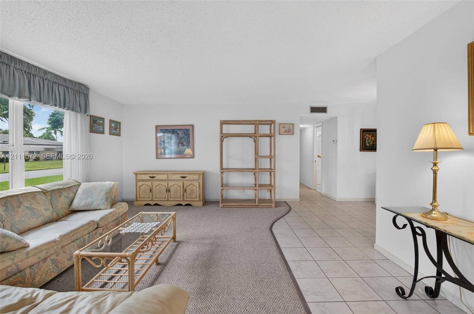 Living area featuring expansive impact windows, neutral berber carpeting, and ceramic tile flooring