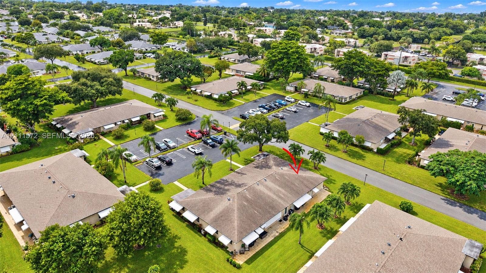 Aerial perspective of a single-story residence featuring a shingled roof, attached exterior awnings, and manicured surrounding lawn area