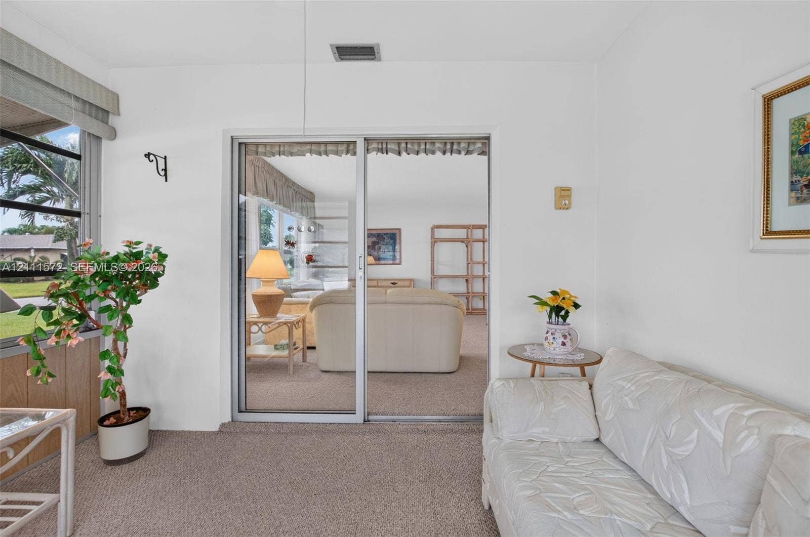 Enjoy your coffee in your enclosed sunroom featuring neutral berber carpeting.
