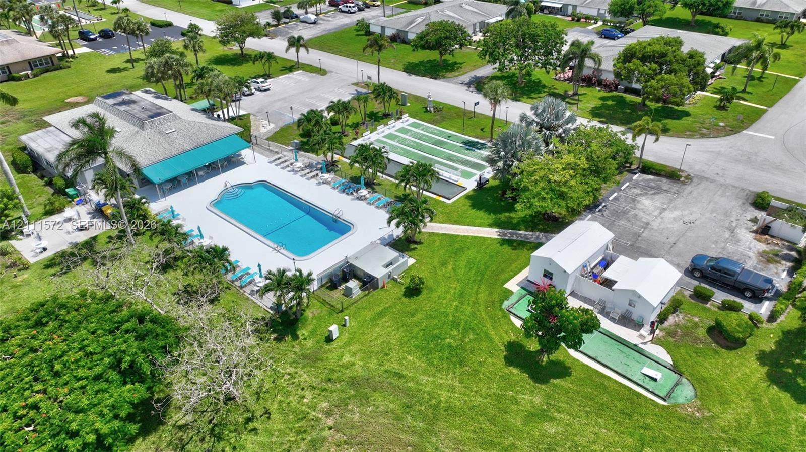 Recreational complex featuring a clubhouse, heated swimming pool with concrete decking, shuffleboard & bocce ball courts