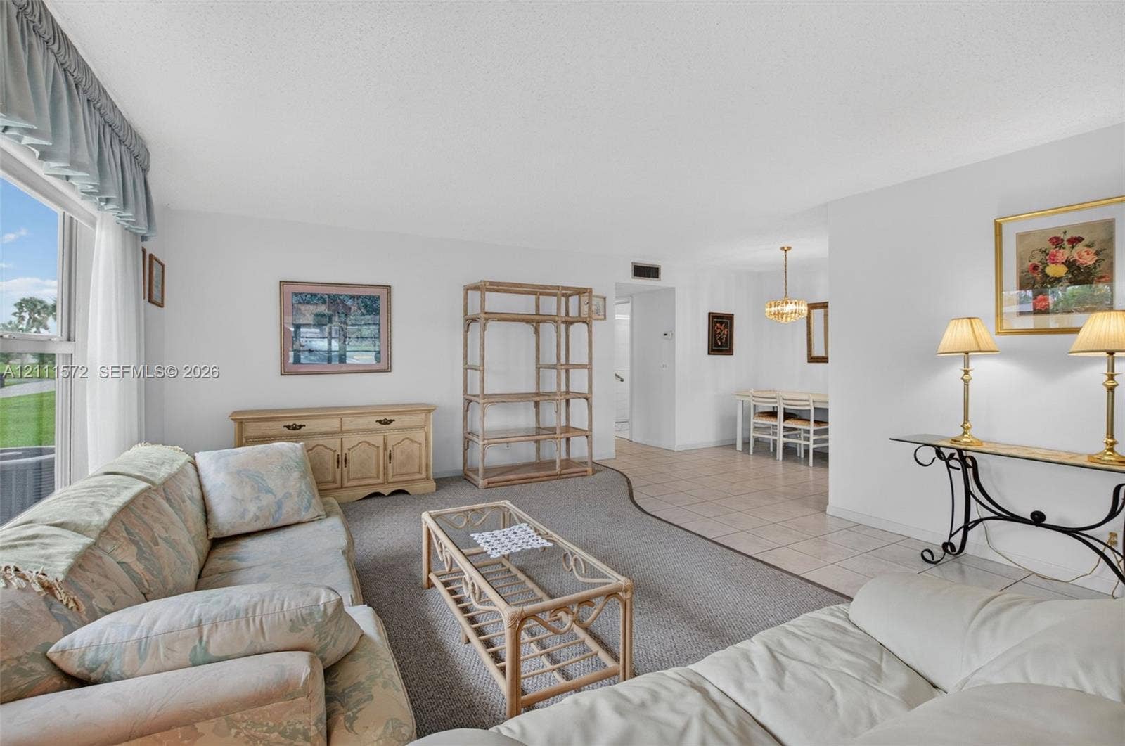 Neutral-toned berber carpeting, tiled flooring, multi-pane window, and suspended overhead chandelier