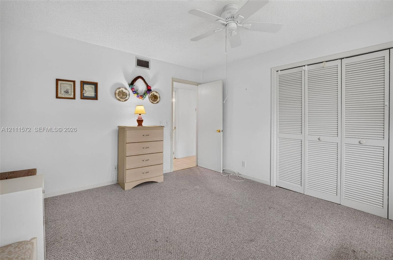 Room featuring wall-to-wall berber carpeting, ceiling fan, and triple-panel louvered closet doors, and large impact windows providing natural light, energy efficiency