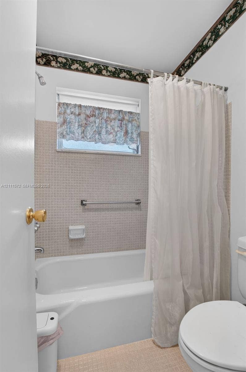 Bathroom featuring a white porcelain tub, square-tiled wall