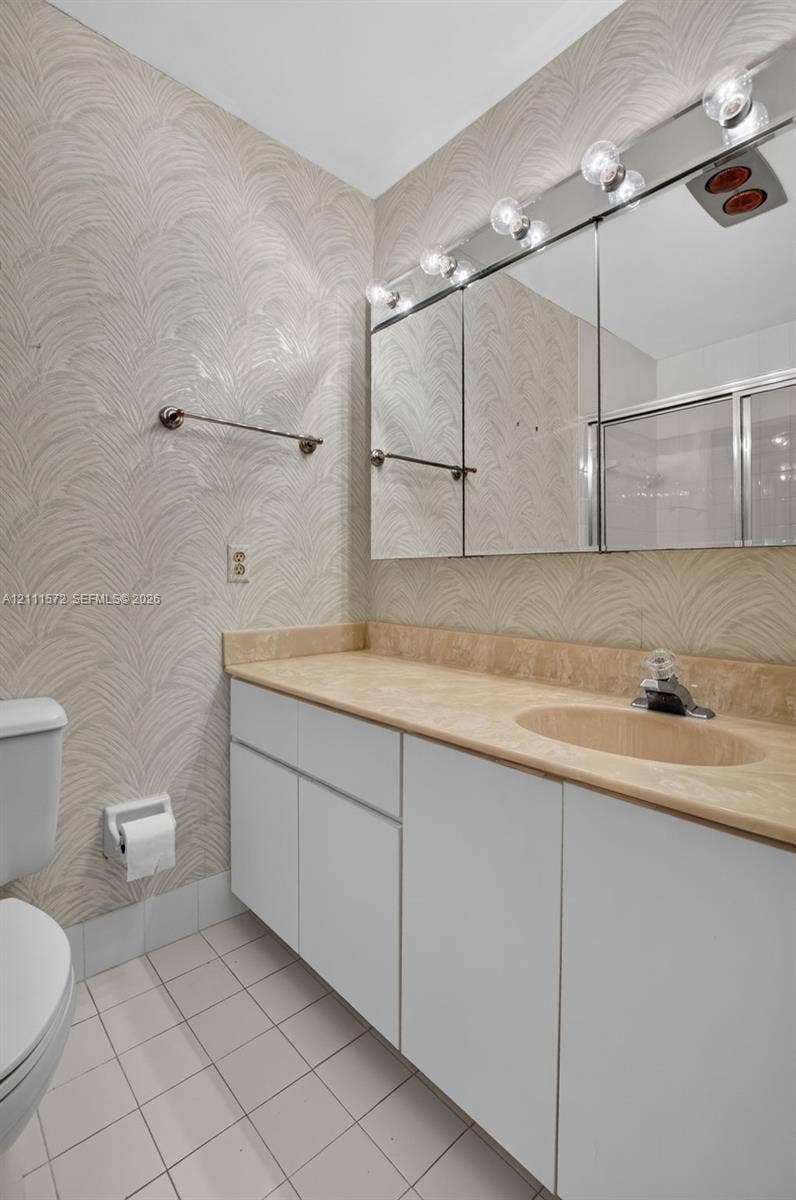 Bathroom featuring multi-panel medicine cabinet with integrated vanity lighting