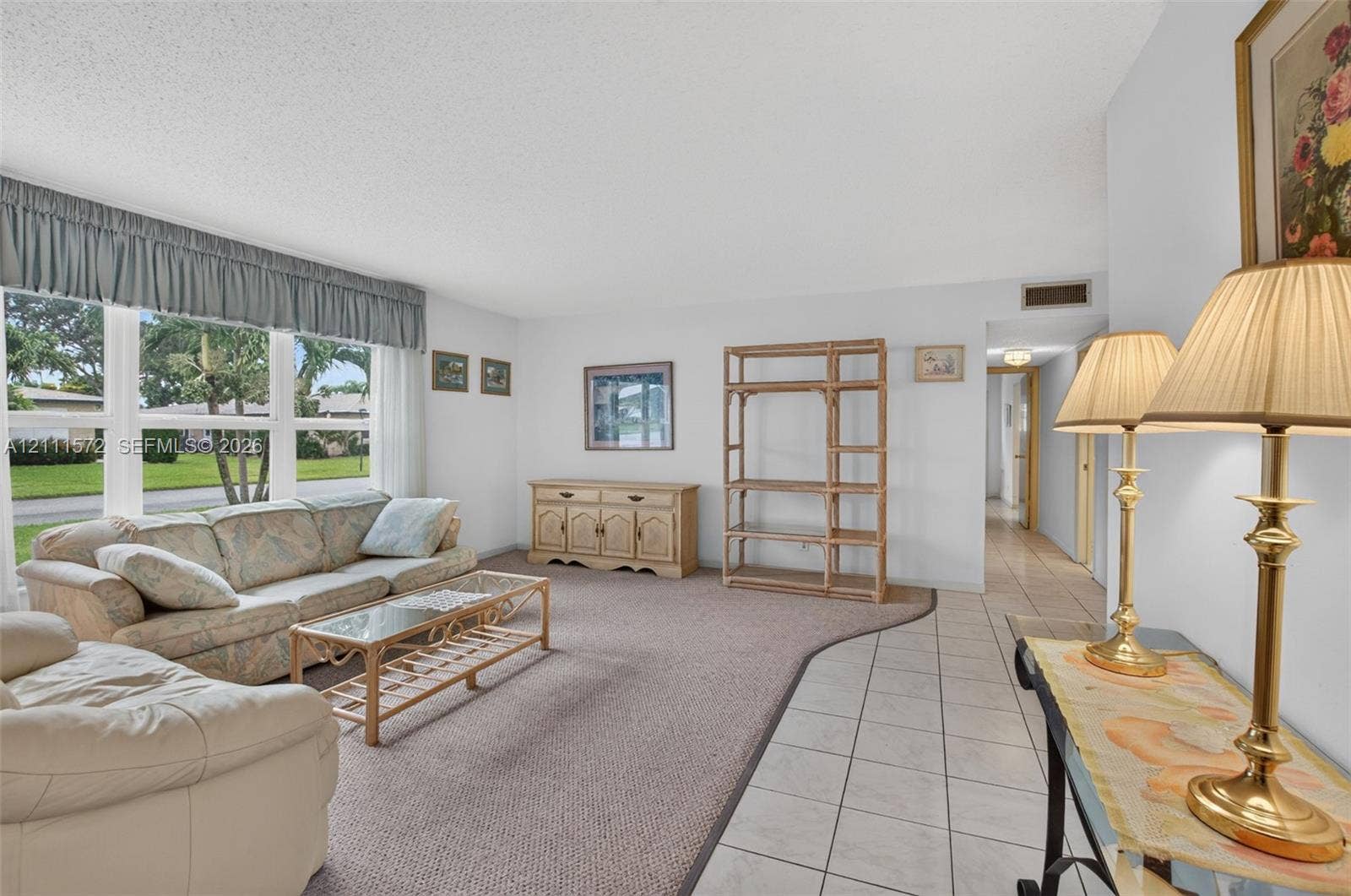 Living area featuring large impact windows with valance treatments, berber carpeting, and ceramic tile flooring.