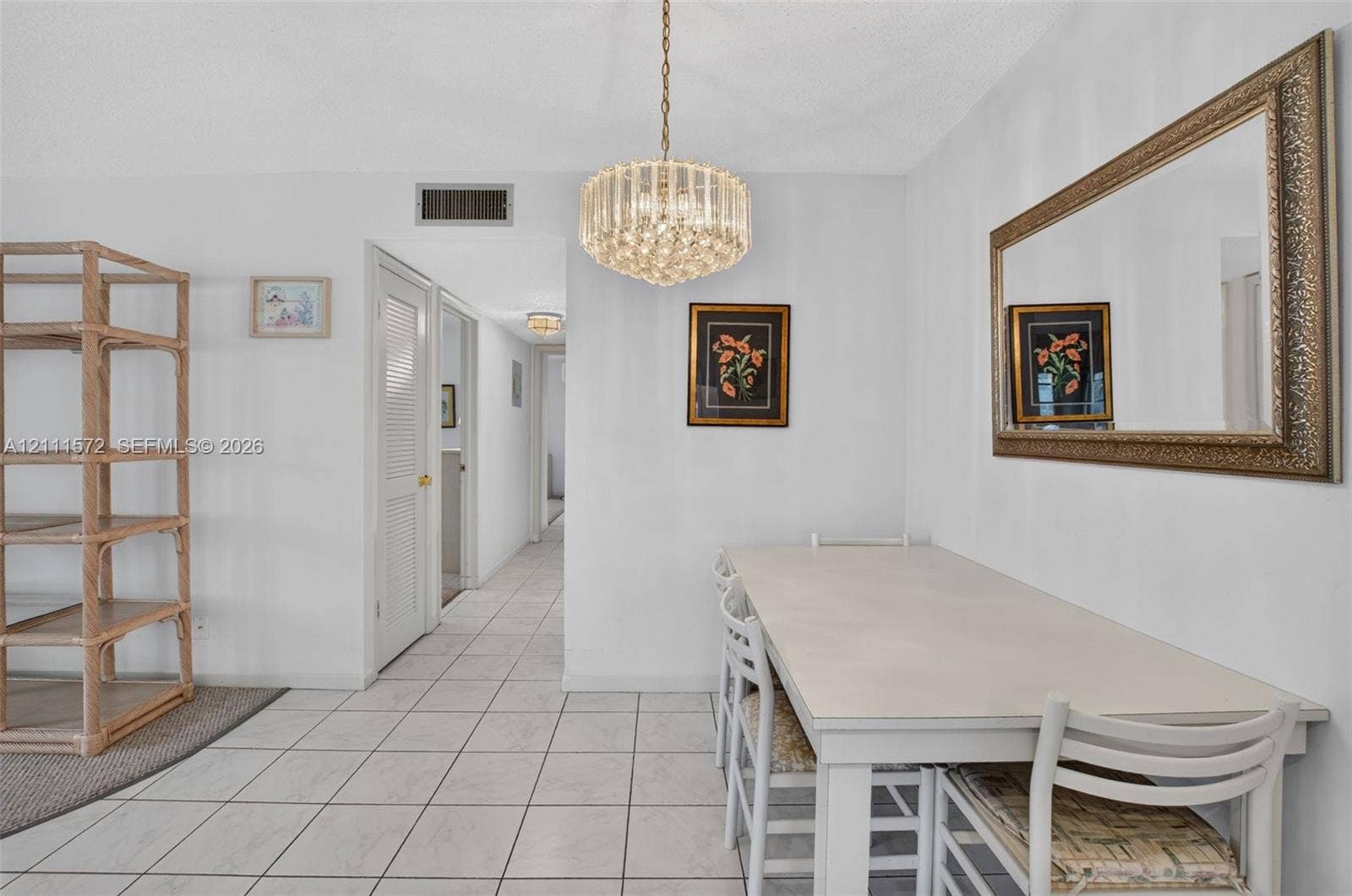 Dining area with neutral tile flooring and a multi-tiered crystal chandelier