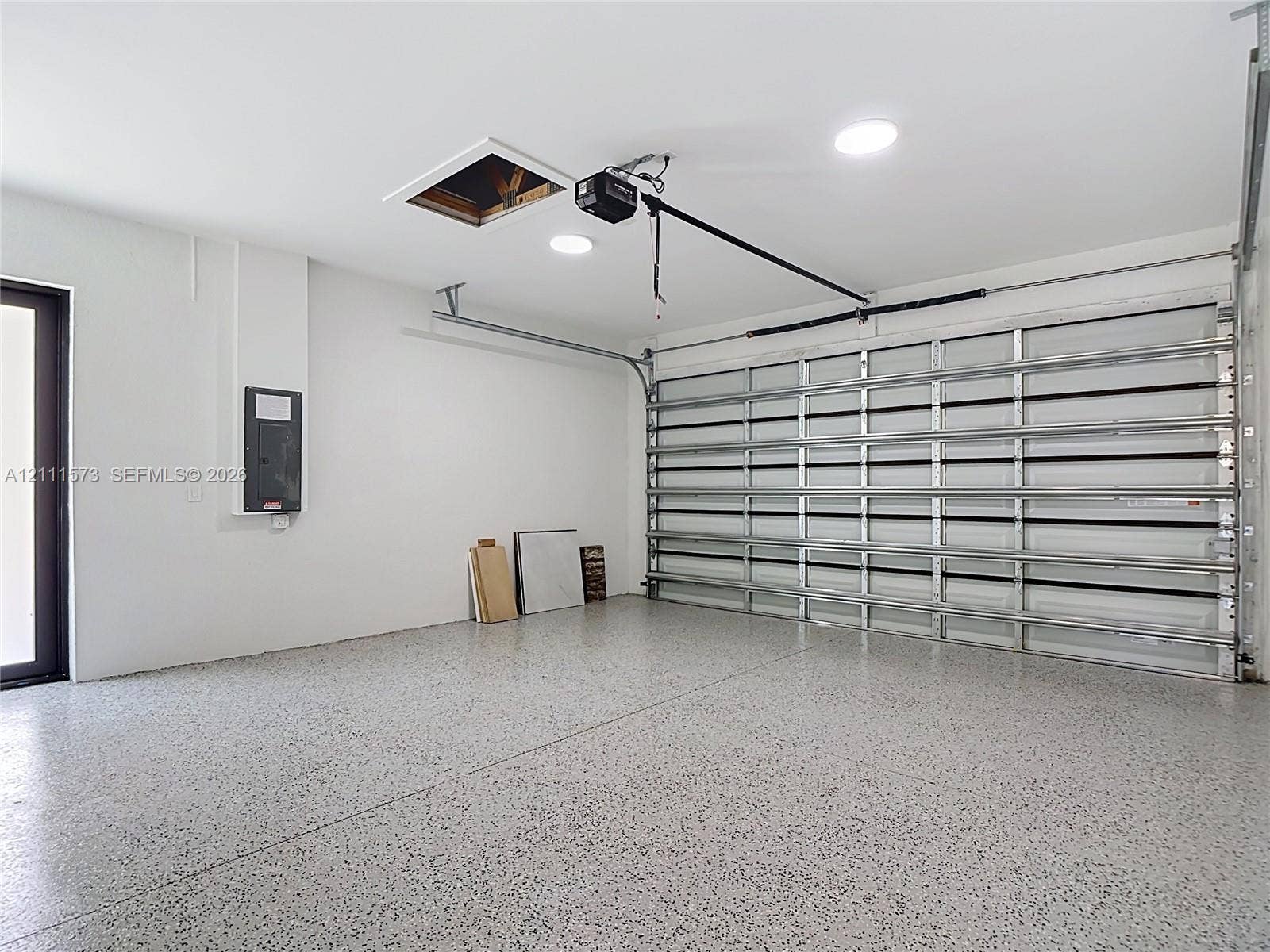 3813 SW 26th Street, Lehigh Acres, FL 33976 Garage space featuring an epoxy-coated floor, sectional garage door, recessed lighting, and direct-access exterior door