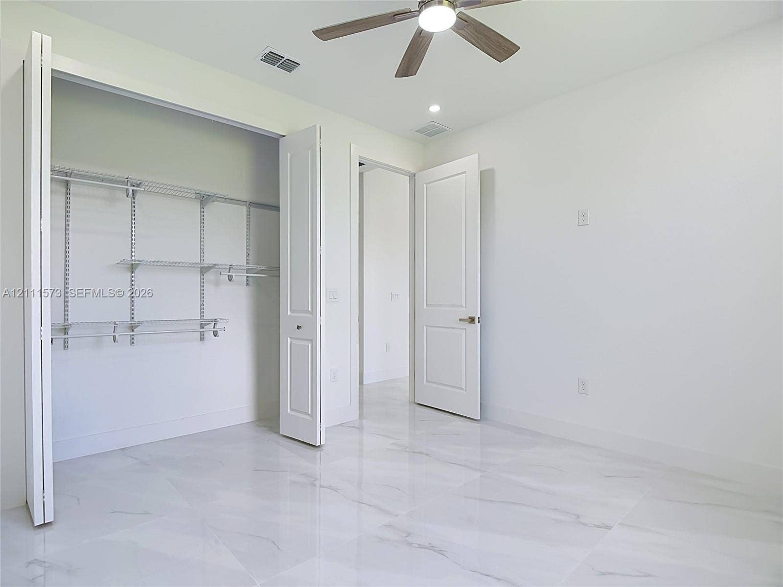 3813 SW 26th Street, Lehigh Acres, FL 33976 Large-format tile flooring, multi-panel doors, ceiling fan with integrated lighting, and built-in closet shelving