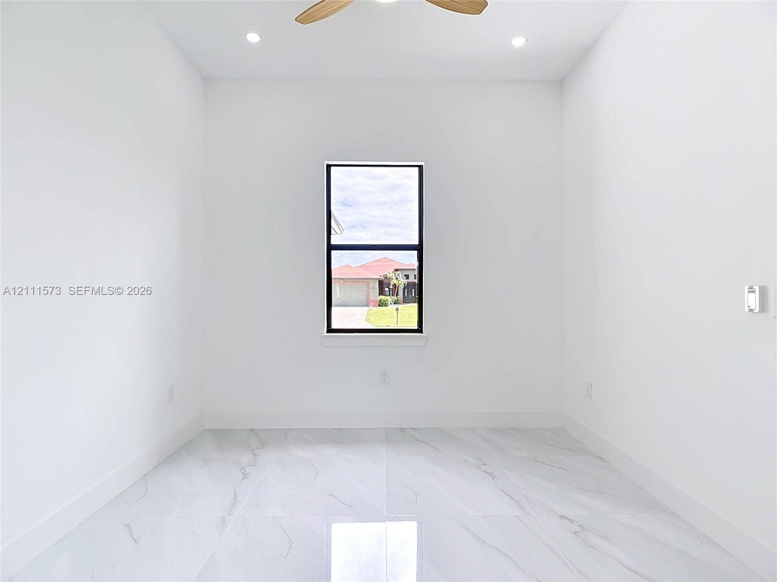 3813 SW 26th Street, Lehigh Acres, FL 33976 Large-format polished tile flooring, central ceiling fan, recessed lighting, and single-pane window with black framing