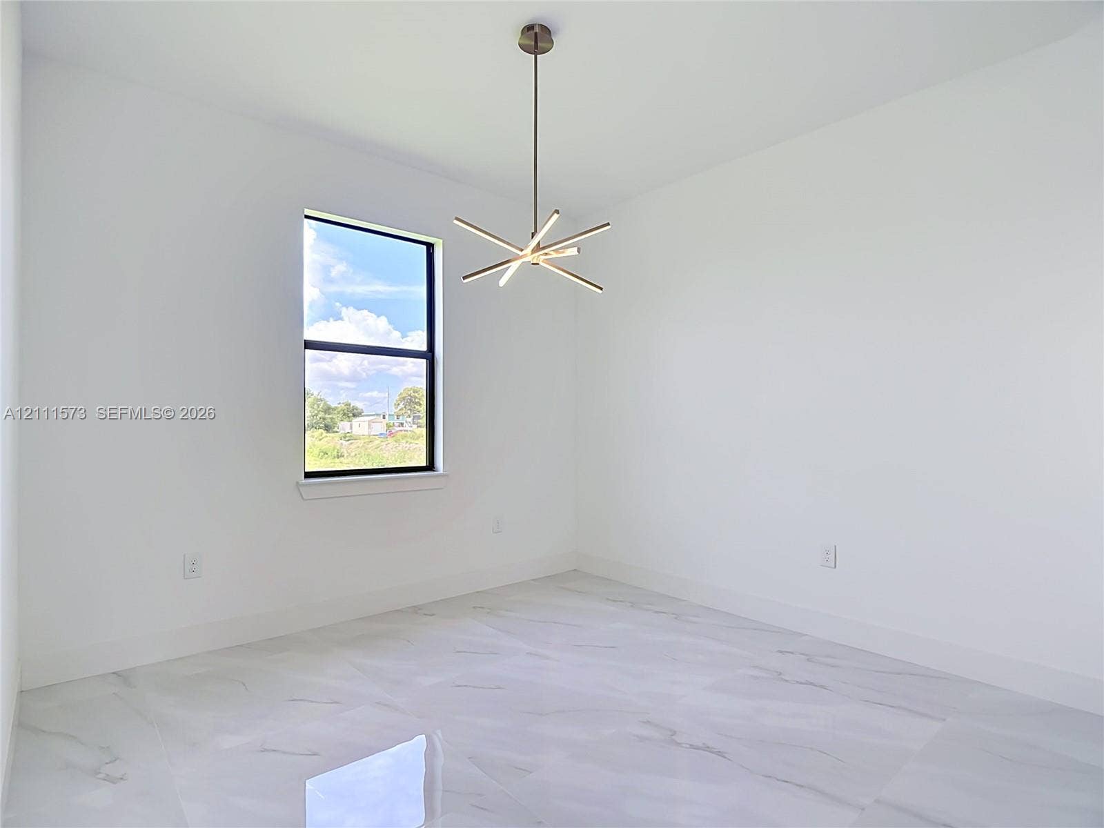 3813 SW 26th Street, Lehigh Acres, FL 33976 Modern room featuring stone-finish tile flooring, a multi-arm linear chandelier, and a single-hung window with a black frame