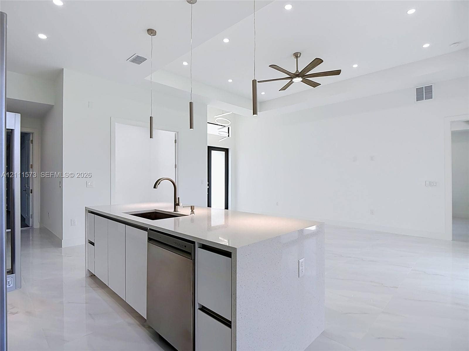 3813 SW 26th Street, Lehigh Acres, FL 33976 Modern kitchen island featuring a light-colored countertop, undermount sink, built-in dishwasher, white cabinetry, and a high-arch faucet, complemented by recessed ceiling lighting, three pendant lights, and a multi-blade ceiling fan