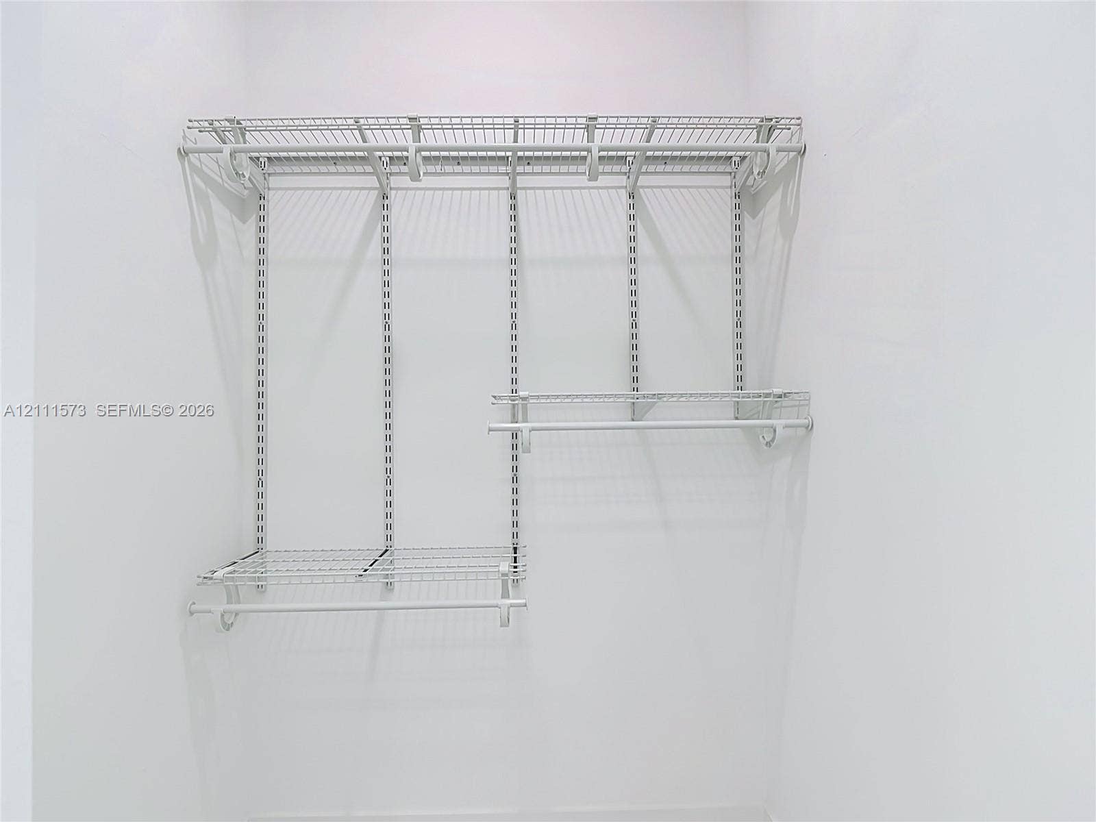 3813 SW 26th Street, Lehigh Acres, FL 33976 White wire shelving system featuring dual-tier hanging rods and adjustable track-mounted supports