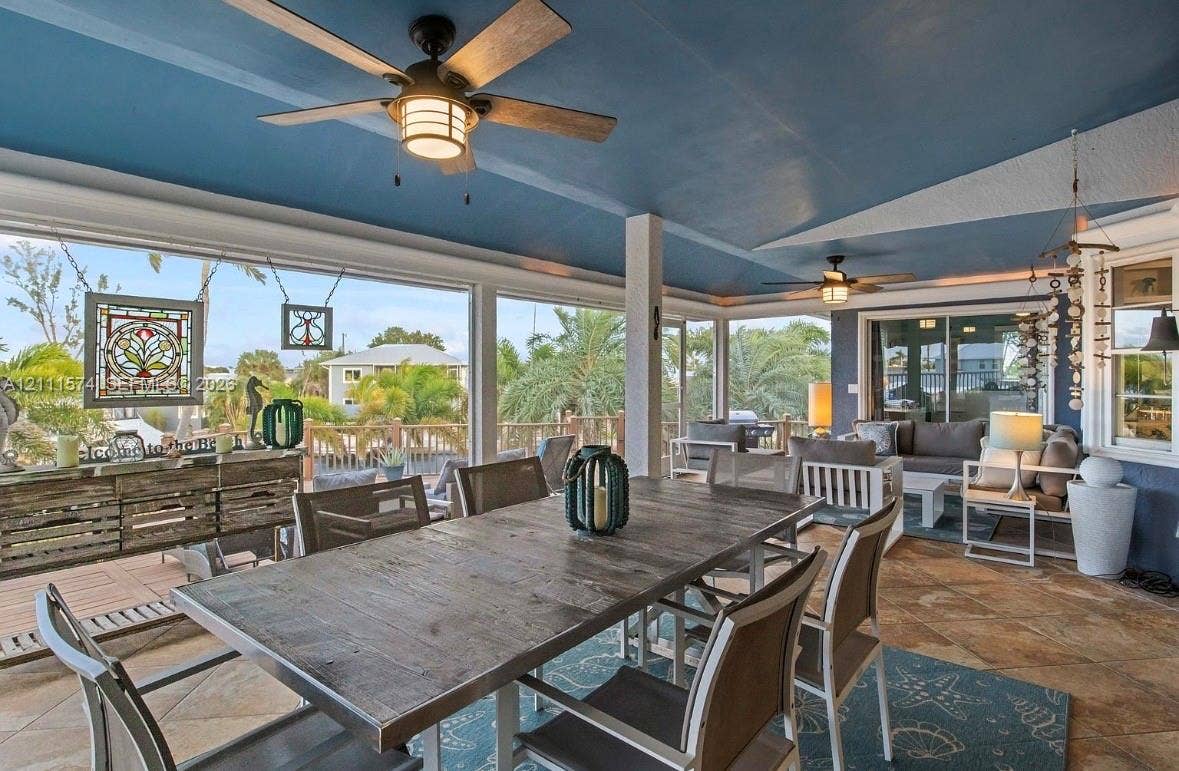 Covered outdoor living area featuring tile flooring, a painted vaulted ceiling, dual ceiling fans, and floor-to-ceiling screened enclosures