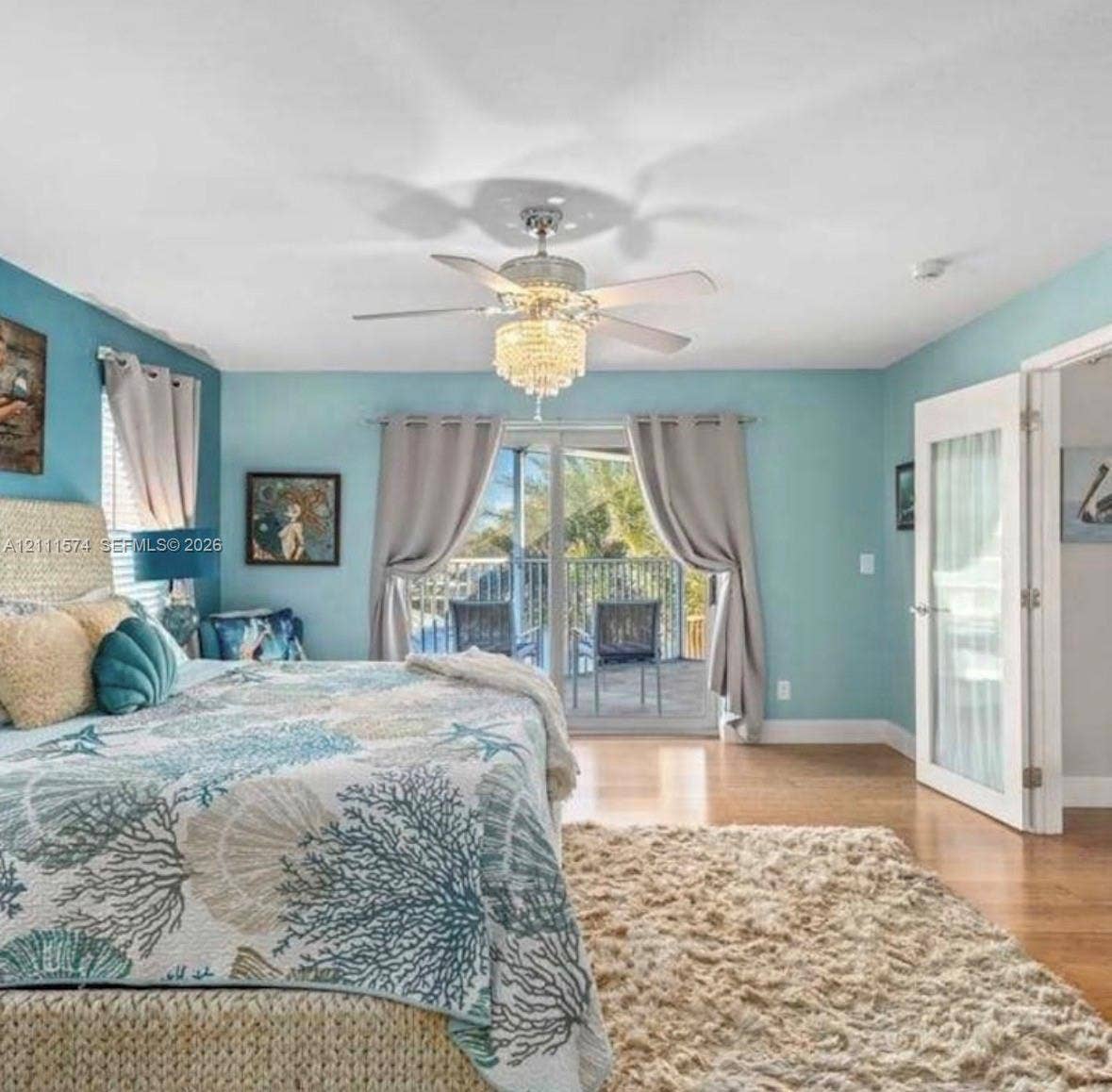 Crystal-style chandelier with a central ceiling fan, wood-finish flooring, and glass-paneled entry door
