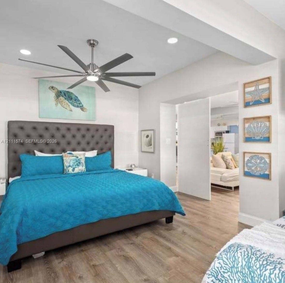 Multi-blade stainless steel ceiling fan with integrated lighting, wood-finish flooring, recessed ceiling lighting, and a neutral color palette