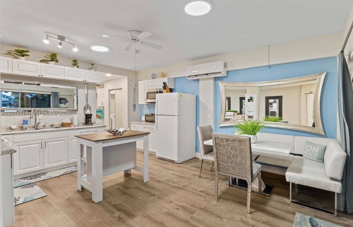 Kitchen featuring white cabinetry, stone-finish countertops, wood-finish flooring, wall-mounted ductless air conditioning unit, and recessed lighting