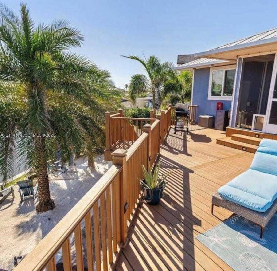 Raised wooden deck with a built-in railing, metal roof overhang, and surrounding palm trees